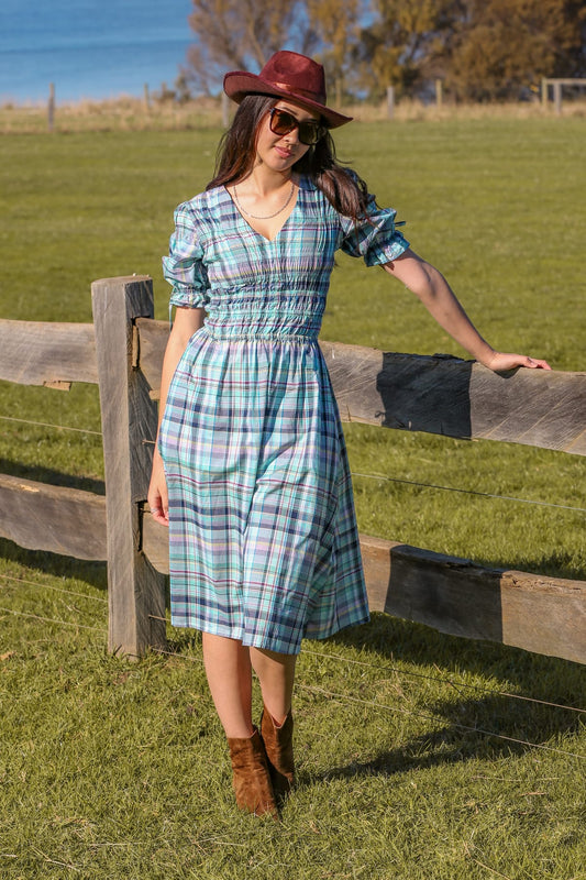 Clairo Meadow lifestyle — heritage plaid cotton dress styled on a tropical island