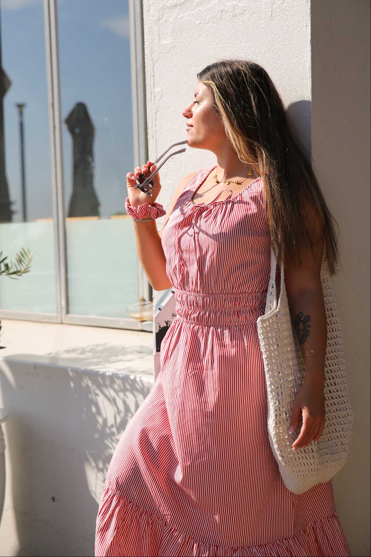 Woman in a pink dress holding a white bag on a balcony