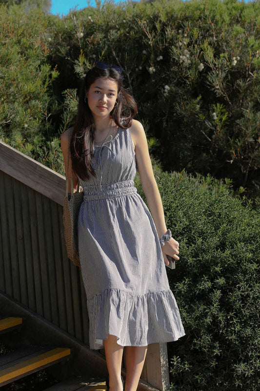 Melina wears the Martina Midnight navy pinstripe midi dress, full length in warm natural light