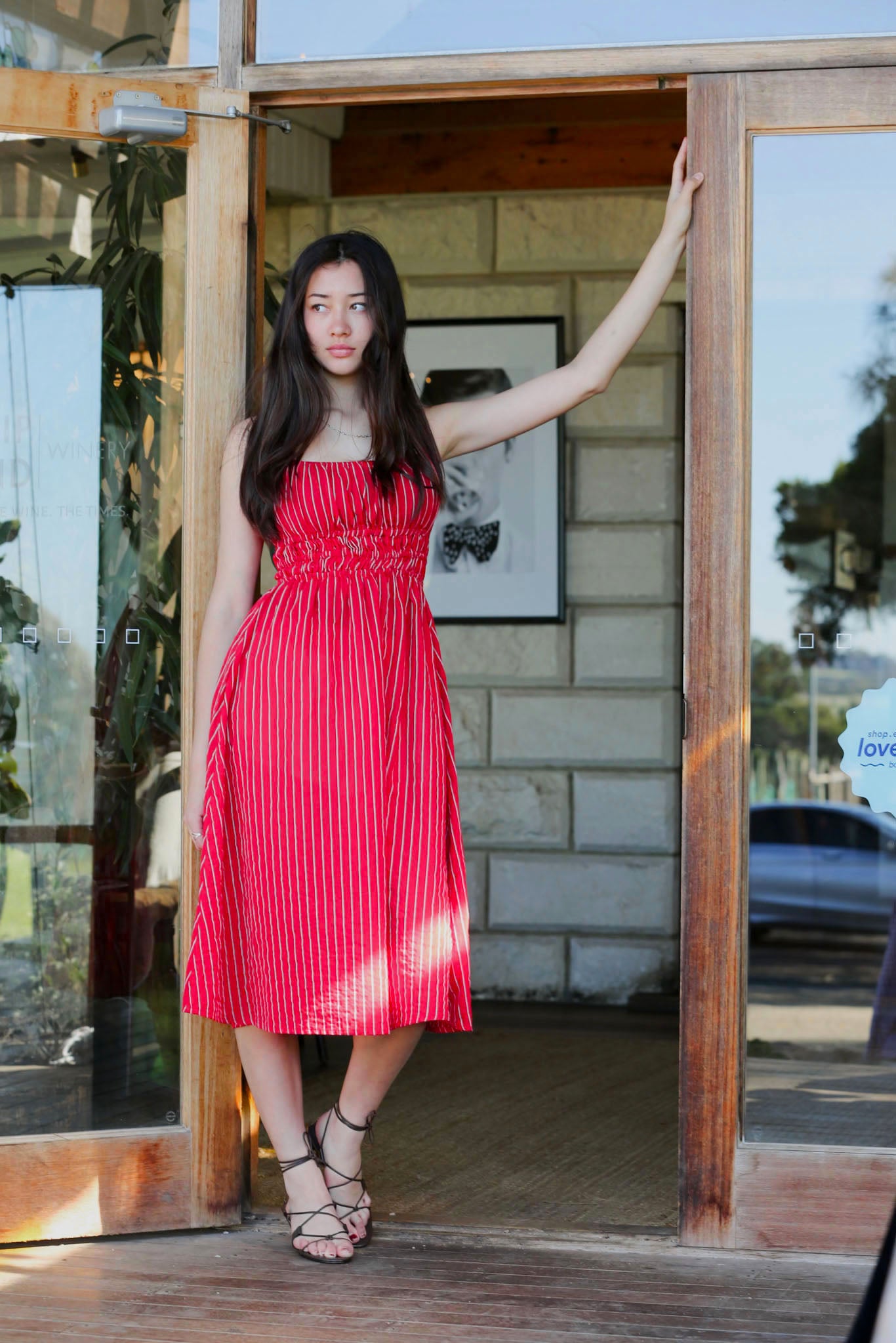 Valentina Scarlet lifestyle — women's red pinstripe cotton midi dress worn at a winery doorway
