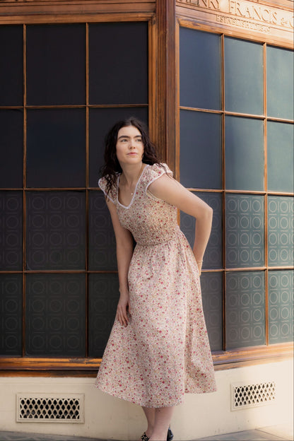 Juliet Wildflower floral cotton midi dress — full-length front view against vintage shopfront in warm afternoon light