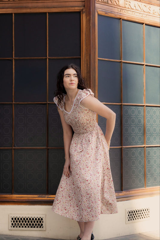 Juliet Wildflower floral cotton midi dress — full-length front view against vintage shopfront in warm afternoon light