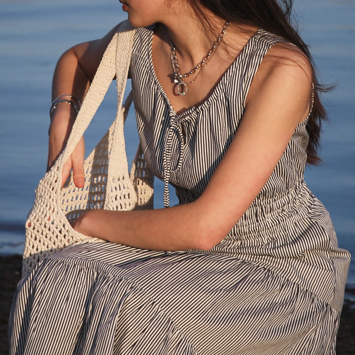 Martina Midnight dress detail, seated with crochet bag