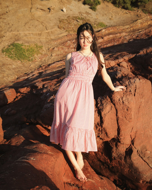 Martina Cherry floral cotton midi dress, standing on coastal rocks
